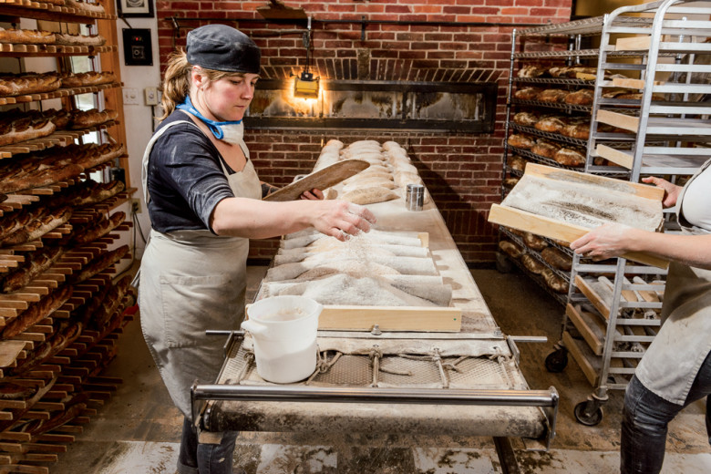 Prepping loaves on the belted loader in front of the custom-built wood-fired oven. 
