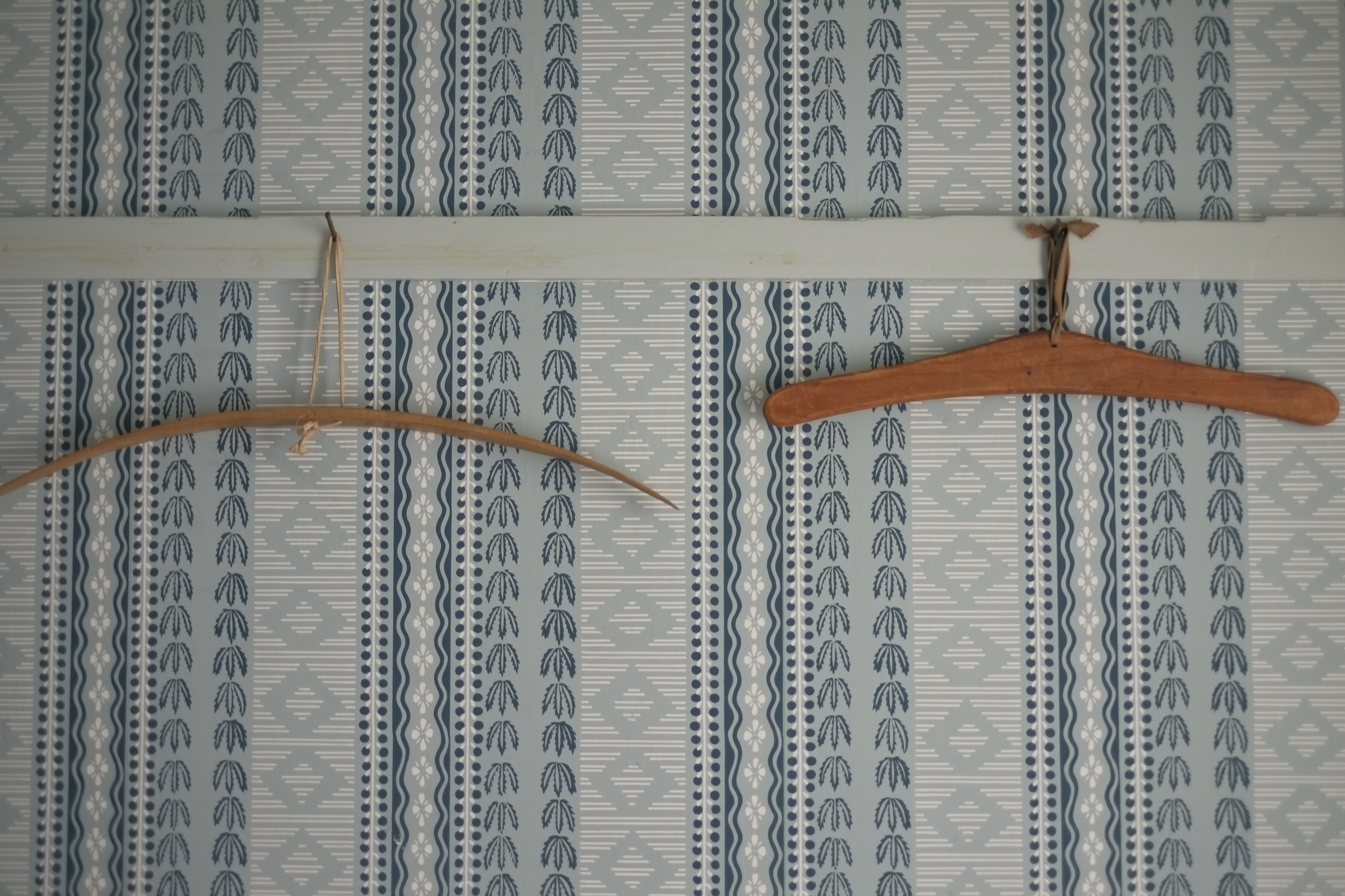 A pair of wooden hangers in the vintage wallpapered closet of an upstairs bedroom at Williams House. 